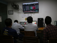 Traders look up at a screen during the Dhaka Stock Exchange trading session at a Brokerage House in Dhaka, Bangladesh, on October 22, 2024....