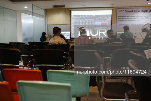 Traders look up at a screen during the Dhaka Stock Exchange trading session at a Brokerage House in Dhaka, Bangladesh, on October 22, 2024. 