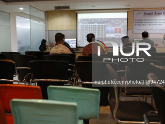 Traders look up at a screen during the Dhaka Stock Exchange trading session at a Brokerage House in Dhaka, Bangladesh, on October 22, 2024....