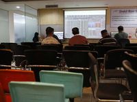 Traders look up at a screen during the Dhaka Stock Exchange trading session at a Brokerage House in Dhaka, Bangladesh, on October 22, 2024....