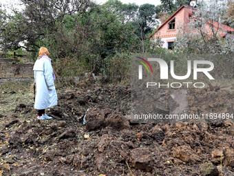 A woman stands at a crater in the ground after the October 18 Russian missile strike in Odesa, Ukraine, on October 19, 2024. (