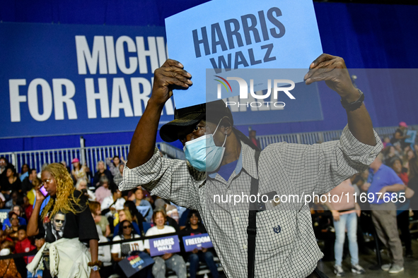 An attendee dances to music while holding a Harris-Walz sign before former President Barack Obama speaks at a presidential campaign rally fo...