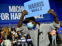 An attendee dances to music while holding a Harris-Walz sign before former President Barack Obama speaks at a presidential campaign rally fo...