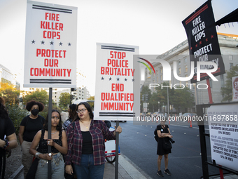 Protesters hold signs during the National Day of Protest to Stop Police Brutality in Washington, D.C., United States, on October 22, 2024. P...