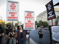 Protesters hold signs during the National Day of Protest to Stop Police Brutality in Washington, D.C., United States, on October 22, 2024. P...