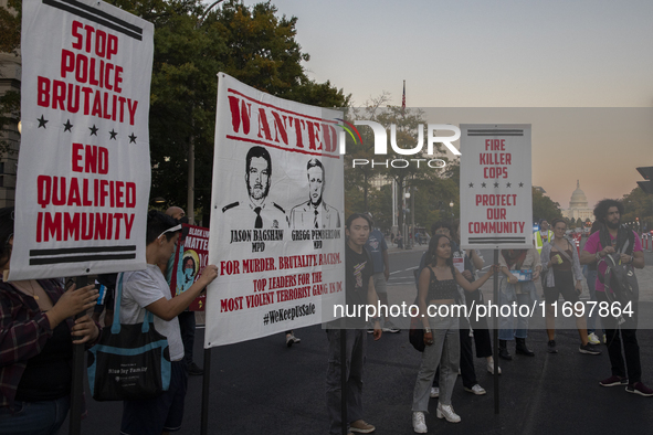 Protesters hold signs during the National Day of Protest to Stop Police Brutality in Washington, D.C., United States, on October 22, 2024. P...