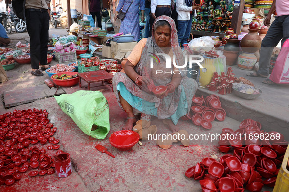 A woman vendor colors earthen lamps 'Diyas' at her roadside shop ahead of the Diwali Festival in Jaipur, Rajasthan, India, on October 23, 20...