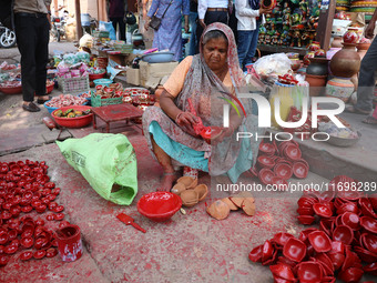 A woman vendor colors earthen lamps 'Diyas' at her roadside shop ahead of the Diwali Festival in Jaipur, Rajasthan, India, on October 23, 20...