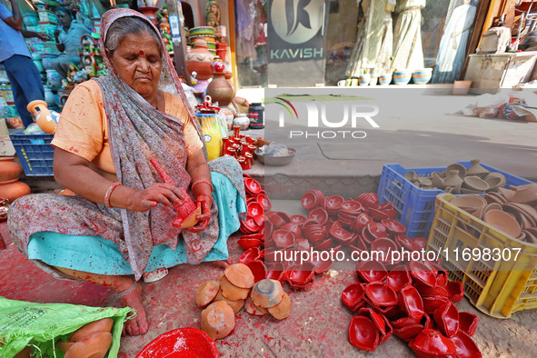 A woman vendor colors earthen lamps 'Diyas' at her roadside shop ahead of the Diwali Festival in Jaipur, Rajasthan, India, on October 23, 20...