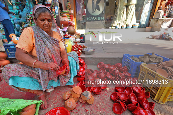 A woman vendor colors earthen lamps 'Diyas' at her roadside shop ahead of the Diwali Festival in Jaipur, Rajasthan, India, on October 23, 20...