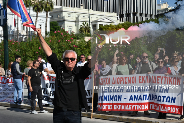 A protester holds a flare as kindergarten and primary school teachers demonstrate in front of the Greek Parliament demanding salary increase...