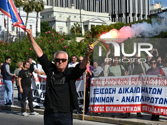 A protester holds a flare as kindergarten and primary school teachers demonstrate in front of the Greek Parliament demanding salary increase...