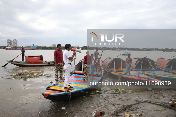 A member of the Kolkata river traffic police uses a megaphone to appeal to people to move to a safer place ahead of Cyclone Dana during patr...