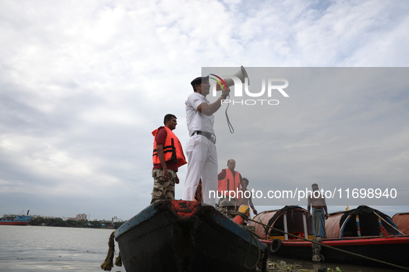 A member of the Kolkata river traffic police uses a megaphone to appeal to people to move to a safer place ahead of Cyclone Dana during patr...