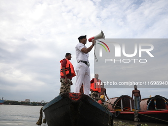 A member of the Kolkata river traffic police uses a megaphone to appeal to people to move to a safer place ahead of Cyclone Dana during patr...