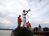 A member of the Kolkata river traffic police uses a megaphone to appeal to people to move to a safer place ahead of Cyclone Dana during patr...