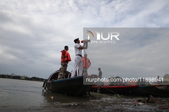 A member of the Kolkata river traffic police uses a megaphone to appeal to people to move to a safer place ahead of Cyclone Dana during patr...