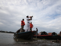 A member of the Kolkata river traffic police uses a megaphone to appeal to people to move to a safer place ahead of Cyclone Dana during patr...