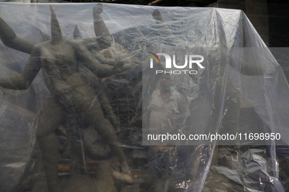 A worker covers idols of the Hindu goddess Kali with a plastic sheet ahead of Cyclone Dana in Kolkata, India, on October 23, 2024. The Regio...