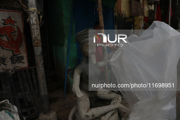 A worker covers an idol of the Hindu goddess Kali with a plastic sheet ahead of Cyclone Dana in Kolkata, India, on October 23, 2024. The Reg...