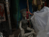 A worker covers an idol of the Hindu goddess Kali with a plastic sheet ahead of Cyclone Dana in Kolkata, India, on October 23, 2024. The Reg...