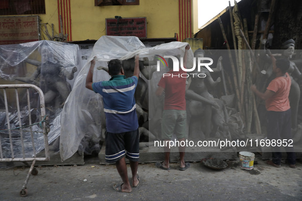 Workers cover idols of the Hindu goddess Kali with a plastic sheet ahead of Cyclone Dana in Kolkata, India, on October 23, 2024. The Regiona...