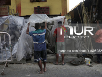 Workers cover idols of the Hindu goddess Kali with a plastic sheet ahead of Cyclone Dana in Kolkata, India, on October 23, 2024. The Regiona...