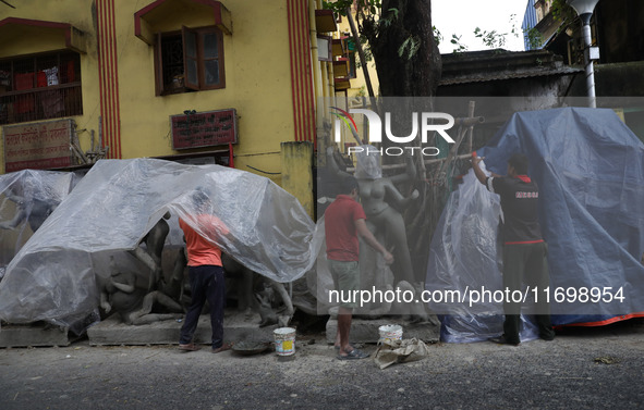 Workers cover idols of the Hindu goddess Kali with a plastic sheet ahead of Cyclone Dana in Kolkata, India, on October 23, 2024. The Regiona...