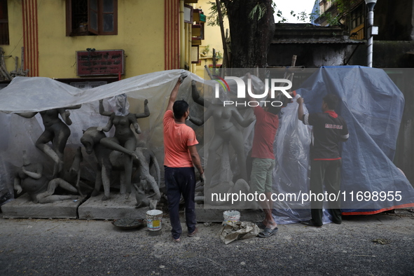 Workers cover idols of the Hindu goddess Kali with a plastic sheet ahead of Cyclone Dana in Kolkata, India, on October 23, 2024. The Regiona...