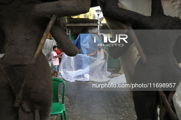 Workers cover idols of the Hindu goddess Kali with a plastic sheet ahead of Cyclone Dana in Kolkata, India, on October 23, 2024. The Regiona...