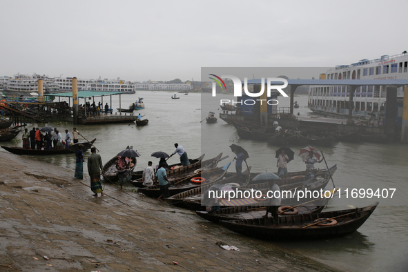 Boatmen wait for passengers on the bank of the Buriganga River during the rainfall in Dhaka, Bangladesh, on October 23, 2024. 