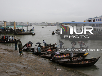 Boatmen wait for passengers on the bank of the Buriganga River during the rainfall in Dhaka, Bangladesh, on October 23, 2024. (