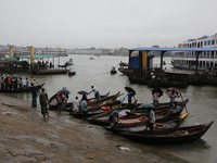 Boatmen wait for passengers on the bank of the Buriganga River during the rainfall in Dhaka, Bangladesh, on October 23, 2024. (