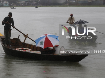 Residents cross over the Buriganga River by boat during the rainfall in Dhaka, Bangladesh, on October 23, 2024. (