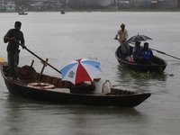 Residents cross over the Buriganga River by boat during the rainfall in Dhaka, Bangladesh, on October 23, 2024. (