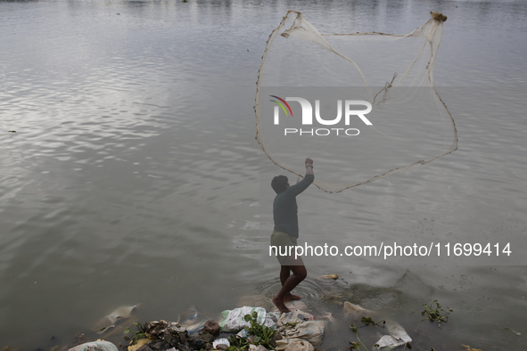 A man casts his fishing net in the Buriganga River in Dhaka, Bangladesh, on October 23, 2024. 