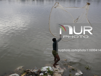 A man casts his fishing net in the Buriganga River in Dhaka, Bangladesh, on October 23, 2024. (