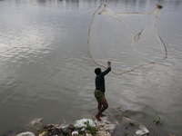 A man casts his fishing net in the Buriganga River in Dhaka, Bangladesh, on October 23, 2024. (