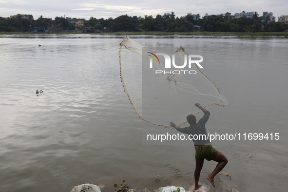 A man casts his fishing net in the Buriganga River in Dhaka, Bangladesh, on October 23, 2024. 