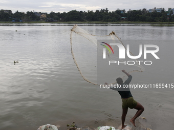 A man casts his fishing net in the Buriganga River in Dhaka, Bangladesh, on October 23, 2024. (