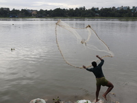 A man casts his fishing net in the Buriganga River in Dhaka, Bangladesh, on October 23, 2024. (