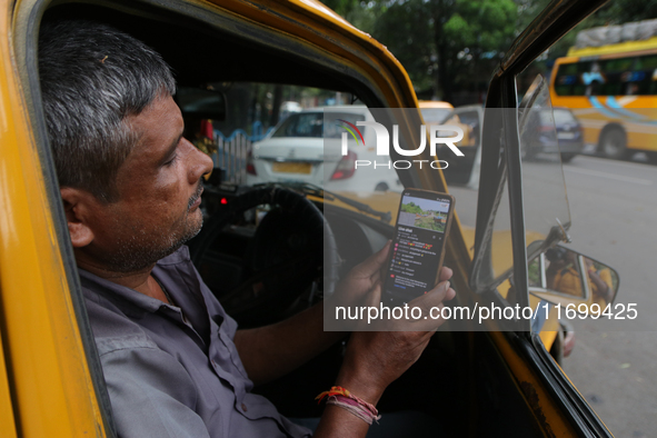 A taxi driver watches his smartphone for the latest update on Cyclone Dana in Kolkata, India, on October 23, 2024. The IMD predicts on Wedne...