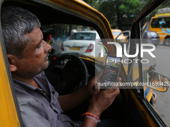 A taxi driver watches his smartphone for the latest update on Cyclone Dana in Kolkata, India, on October 23, 2024. The IMD predicts on Wedne...