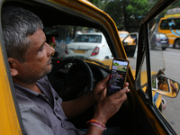 A taxi driver watches his smartphone for the latest update on Cyclone Dana in Kolkata, India, on October 23, 2024. The IMD predicts on Wedne...