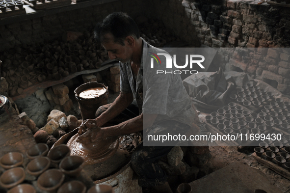 An Indian potter prepares a diya (earthen lamp) at Kumbharwada potter's colony of Dharavi slum in preparation for Diwali (Hindu festival of...