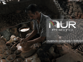 An Indian potter prepares a diya (earthen lamp) at Kumbharwada potter's colony of Dharavi slum in preparation for Diwali (Hindu festival of...