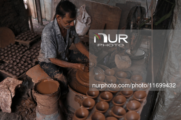 An Indian potter prepares a diya (earthen lamp) at Kumbharwada potter's colony of Dharavi slum in preparation for Diwali (Hindu festival of...