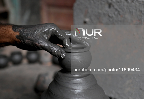 An Indian potter prepares an earthen pot to perform Laxmi Pooja at Kumbharwada potter's colony of Dharavi slum in preparation for Diwali, th...