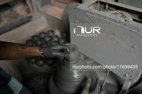 An Indian potter prepares an earthen pot to perform Laxmi Pooja at Kumbharwada potter's colony of Dharavi slum in preparation for Diwali, th...