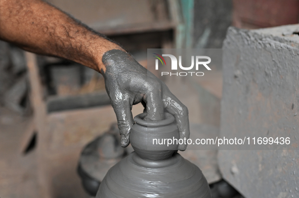 An Indian potter prepares an earthen pot to perform Laxmi Pooja at Kumbharwada potter's colony of Dharavi slum in preparation for Diwali, th...